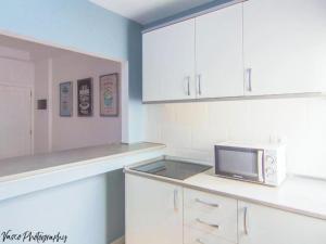 una cocina con armarios blancos y microondas en una encimera en Live Puertito Mar Y Muelle, en Puertito de Güímar