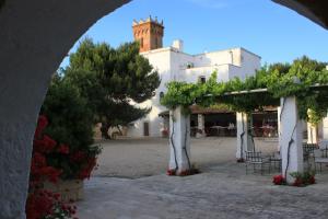 an archway with a building and trees and a church at Masseria Incantalupi in San Vito dei Normanni