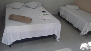 2 camas con sábanas blancas y toallas. en GRAN HOTEL en Três Lagoas