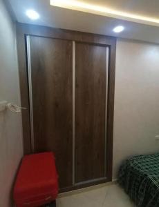 a bedroom with a wooden closet and a red stool at Dayar arrid in Nador