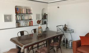 ein Esszimmer mit einem Tisch, Stühlen und Bücherregalen in der Unterkunft Appartement agréable avec 2 très belles terrasses au coeur de Rabat in Rabat