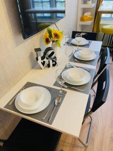 uma mesa com pratos e óculos e um vaso com girassóis em Lovely HotelStyle Apartment - Central London em Londres