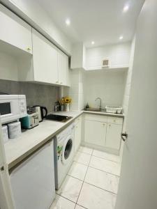 uma cozinha com armários brancos e uma máquina de lavar roupa em Lovely HotelStyle Apartment - Central London em Londres