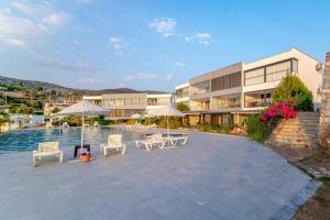 a building with chairs and umbrellas next to a pool at Vacation Flat w Pool Garden in Bodrum in Milas