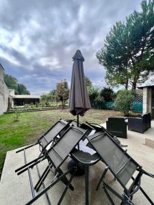 two chairs and an umbrella on a patio at Charmante & Paisible Villa Platon - Jacuzzi & Jardin - Brive in Brive-la-Gaillarde