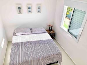 ein Schlafzimmer mit einem Bett und einem Fenster in der Unterkunft Casa Marola: 100M da Praia, Completa e Tranquila in Bertioga + 29 Fotos