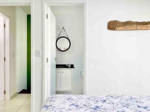 ein Schlafzimmer mit einem Bett und einem Spiegel an der Wand in der Unterkunft Casa Marola: 100M da Praia, Completa e Tranquila in Bertioga