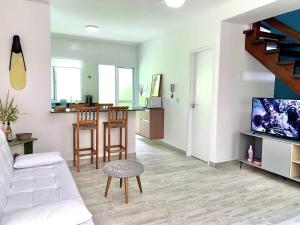 ein Wohnzimmer mit einer weißen Couch und einer Küche in der Unterkunft Casa Maré Mansa: in Bertioga