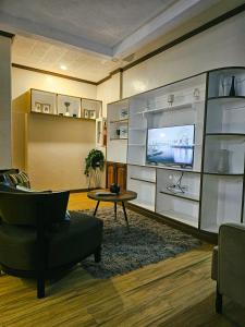 a living room with a tv and a chair and a table at Mirador Modern House - Walking distance to Lourdes Grotto in Baguio