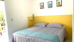 ein Schlafzimmer mit einem Bett mit gelber Wand in der Unterkunft Casa das Marés: 100M Praia da Enseada - Tranquila e Completa in Bertioga