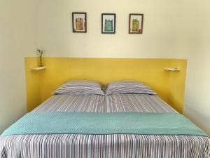 ein Schlafzimmer mit einem Bett mit einem gelben Kopfteil in der Unterkunft Casa das Marés: 100M Praia da Enseada - Tranquila e Completa in Bertioga
