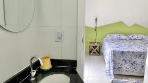ein Badezimmer mit Waschbecken und ein Bett in einem Zimmer in der Unterkunft Casa das Marés: 100M Praia da Enseada - Tranquila e Completa in Bertioga