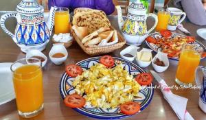 uma mesa coberta com pratos de comida para o pequeno-almoço e sumo de laranja em Caslune 