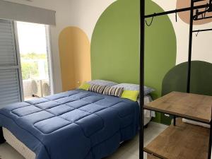 a bedroom with a blue bed and a table at Apto Moderno e Completo a 50m da Praia in Bertioga