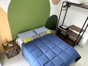a bedroom with a blue bed and a green wall at Apto Moderno e Completo a 50m da Praia in Bertioga