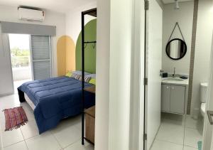a bedroom with a blue bed and a bathroom at Apto Moderno e Completo a 50m da Praia in Bertioga