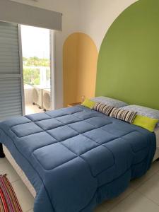 a large blue bed in a room with a window at Apto Moderno e Completo a 50m da Praia in Bertioga
