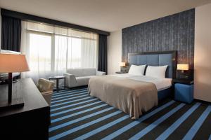 een hotelkamer met een groot bed en een bank bij Van der Valk Hotel Sneek in Sneek