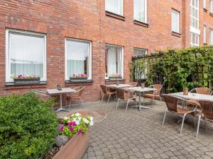 eine Terrasse mit Tischen und Stühlen vor einem Backsteingebäude in der Unterkunft B&B Hotel Duisburg Hbf-Nord in Duisburg