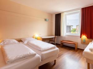 a hotel room with two beds and a window at B&B Hotel Duisburg Hbf-Nord in Duisburg