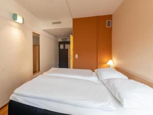 1 Schlafzimmer mit 2 weißen Betten in einem Zimmer in der Unterkunft B&B Hotel Duisburg Hbf-Nord in Duisburg