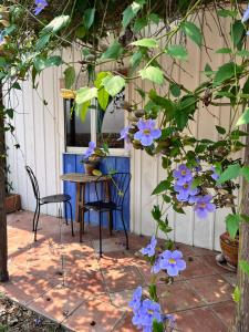 einen Tisch, Stühle und lila Blumen auf einer Terrasse in der Unterkunft Giardino Di Sicilia in SantʼAgata di Militello