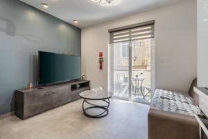 sala de estar con TV de pantalla plana y mesa en Nocturnal Elegance Apartment by Solea, en Sliema