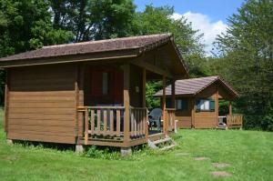 una grande cabina in legno con un portico nell'erba di Camping de Tauves a Tauves