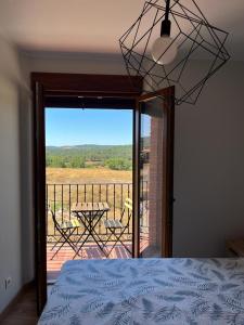 um quarto com uma cama e uma varanda com uma mesa em La Traviesa de la Demanda em Cabezón de la Sierra