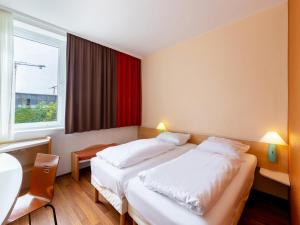ein Hotelzimmer mit 2 Betten und einem Fenster in der Unterkunft B&B Hotel Duisburg Hbf-Nord in Duisburg