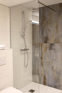 La salle de bains est pourvue d'une douche avec une porte en verre. dans l'établissement La ferme de Berlioz, à La Côte-Saint-André