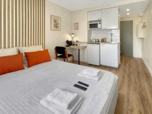 a bedroom with a large white bed and a kitchen at Le Petit Melun in Melun