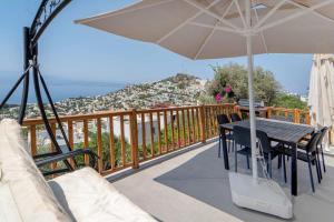 a balcony with a table and an umbrella at Sea View Flat with Terrace 3 min to Beach in Gumusluk