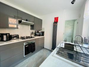cocina con armarios grises y horno con fogones en Lovely 4-Bed House in Luton, en Luton