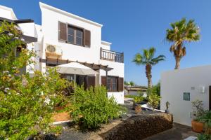 una casa blanca con palmeras en el fondo en Casa Maesa, en Playa Honda