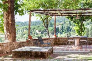 um pátio com uma mesa, cadeiras e uma árvore em Isola del Pittore Fienile di Villa Storica em Grassina