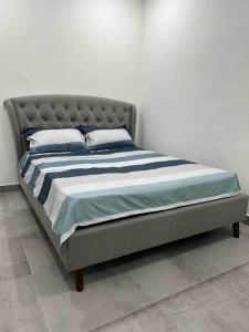 een bed in een slaapkamer met een witte muur bij P3 Great value, cozy, convenient in city! in Kuching