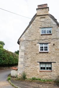 a stone building with two windows on the side of it at Beautiful 3BD Thatched Stone Cottage Kettering in Pytchley