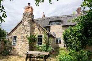 an old stone house with a slate roof at Beautiful 3BD Thatched Stone Cottage Kettering in Pytchley