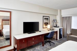 a hotel room with a desk with a television and a bed at Sheraton Indianapolis Hotel at Keystone Crossing in Indianapolis