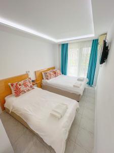twee bedden in een kamer met blauwe gordijnen bij Mercan Otel in Canakkale