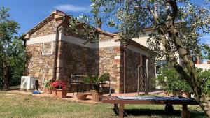 een stenen huis met een bank ervoor bij Monolocale per due Agriturismo le Pinete in Riotorto