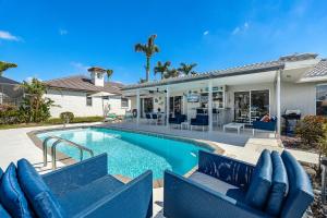 a swimming pool with blue chairs next to a house at Villa Ocean Palm - Cape Coral - Roelens Vacations in Cape Coral