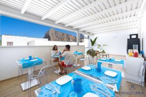 a couple sitting in a restaurant with blue tables at Rivazzurra Beach Rooms in San Vito lo Capo