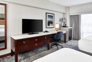 um quarto de hotel com uma secretária e uma televisão de ecrã plano em Sheraton Indianapolis Hotel at Keystone Crossing em Indianápolis