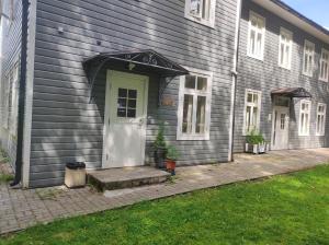 Casa gris con puerta blanca y porche en Elva Stuudiomajutus en Elva