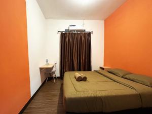 Schlafzimmer mit orangefarbenen Wänden, einem Bett und einem Schreibtisch in der Unterkunft Casa Feby Guest House in Bandung