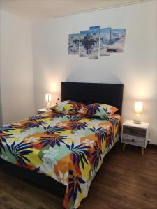 1 Schlafzimmer mit einem Bett mit einer farbenfrohen Tagesdecke und 2 Lampen in der Unterkunft Maison confortable à Ansouis dans Le Luberon in Ansouis