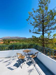 two chairs and a table on a balcony with a tree at Olive tree cottage in Elia Laconias