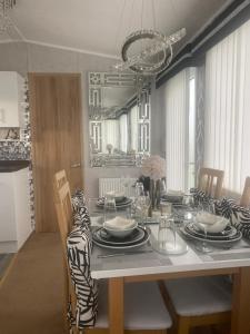 Sandylands Holiday Home في Stevenston: غرفة طعام مع طاولة مع الأطباق والأطباق